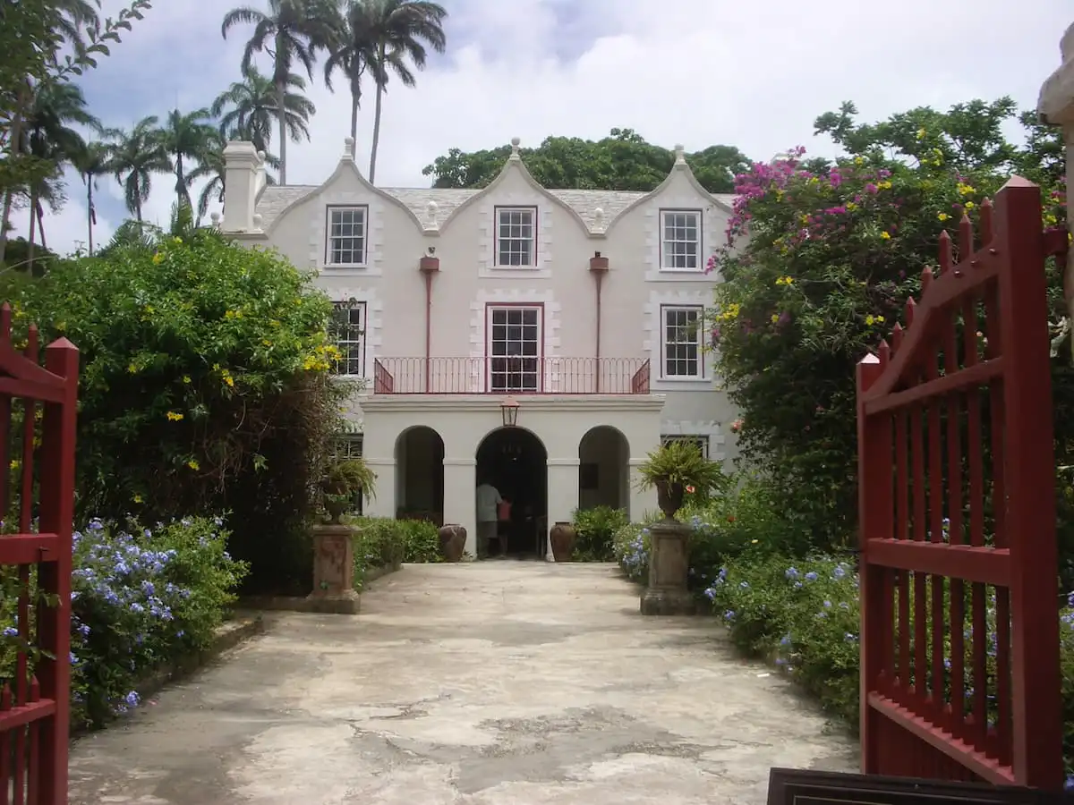 St. Nicholas Abbey surrounded by green trees and flowers with red gate at entrance