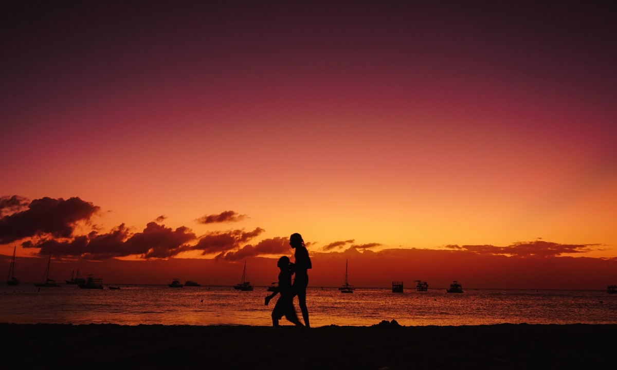 Two people walking on Barbados beach at sunset