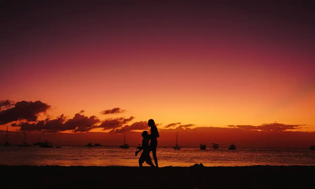 Two people walking on Barbados beach at sunset
