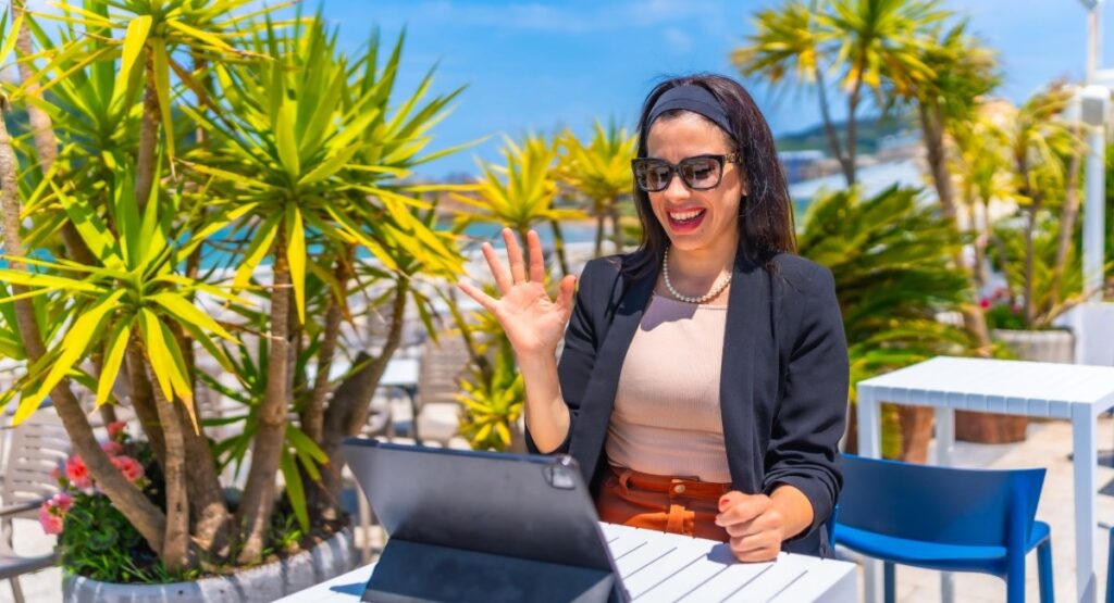 Happy female digital nomad working remotely on laptop in tropical Barbados setting with palm trees - professional woman enjoying Caribbean remote work lifestyle with reliable internet connection