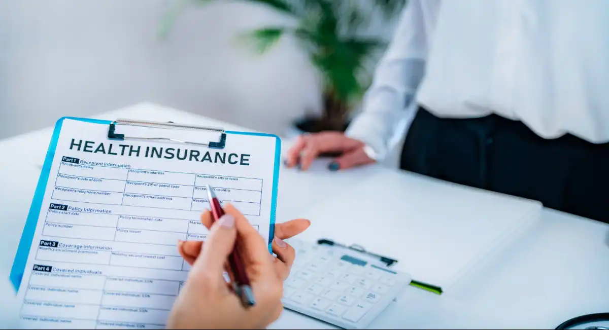 Person completing a private health insurance form for international medical coverage when relocating to Barbados